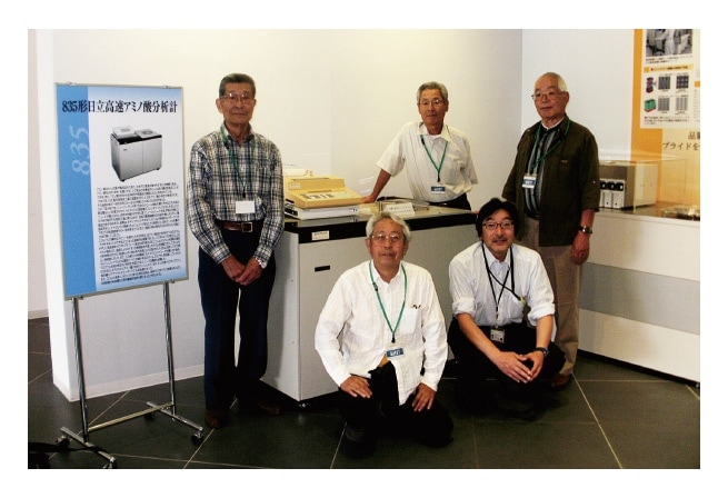 Fig. 2 The Model 835 high-speed amino acid analyzer and its developers. Counterclockwise from left: Dr. Shigetake Ganno, Mr. Yoshio Fujii, Dr. Masahito Matt Ito (an author of this article, not a developer of the Model 835), Mr. Hiroshi Satake, Mr. Akira Numata