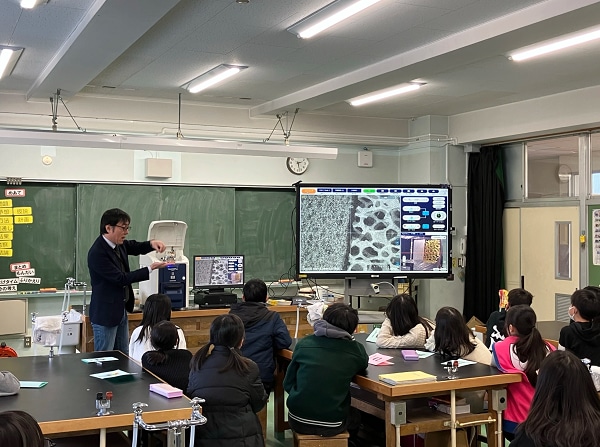 The instructor from Hitachi High-Tech explaining internal structures using an actual tabletop electron microscope