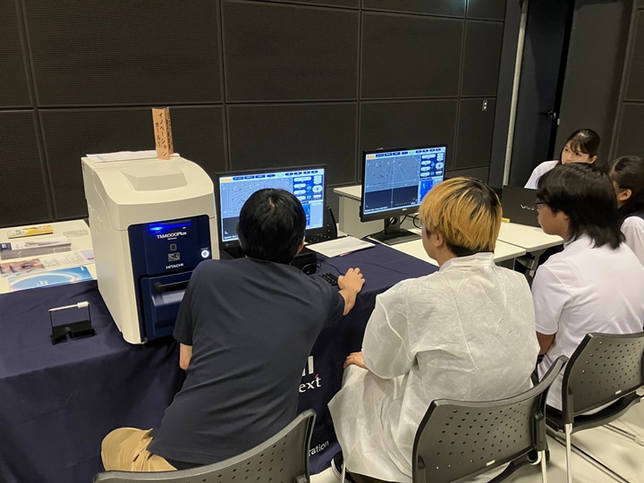 電子顕微鏡で観察した画像を日立ハイテクの社員が説明