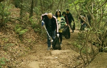 参加者は起伏の多い道を徒歩で移動しながらゴミ収集を実施